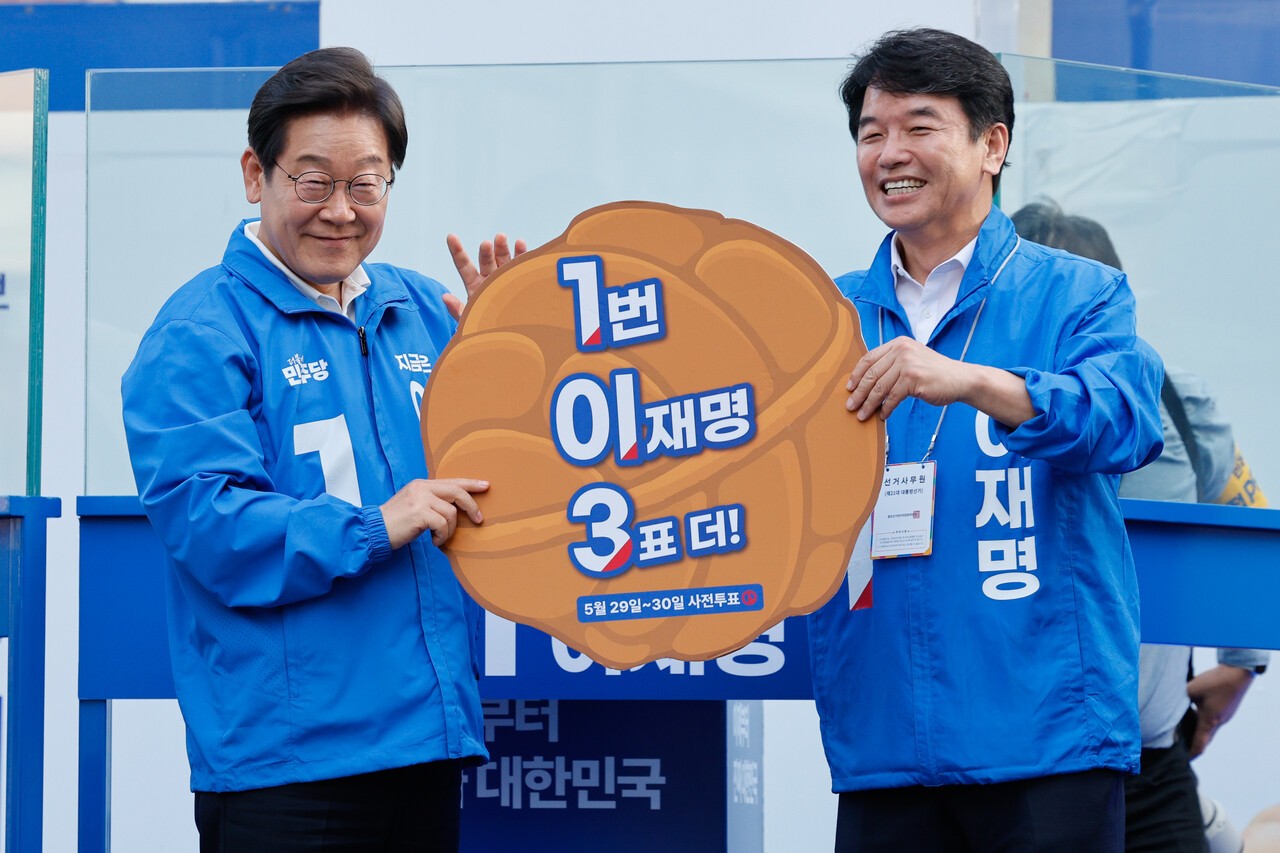 이재명 당시 더불어민주당 대선 후보가 지난 5월 25일 충남 천안시 신부문화거리를 찾아 문진석 충남도당 위원장으로부터 ‘1번 이재명 3표 더!’라고 적힌 호두과자 모양 피켓을 받고 있다. [연합뉴스]