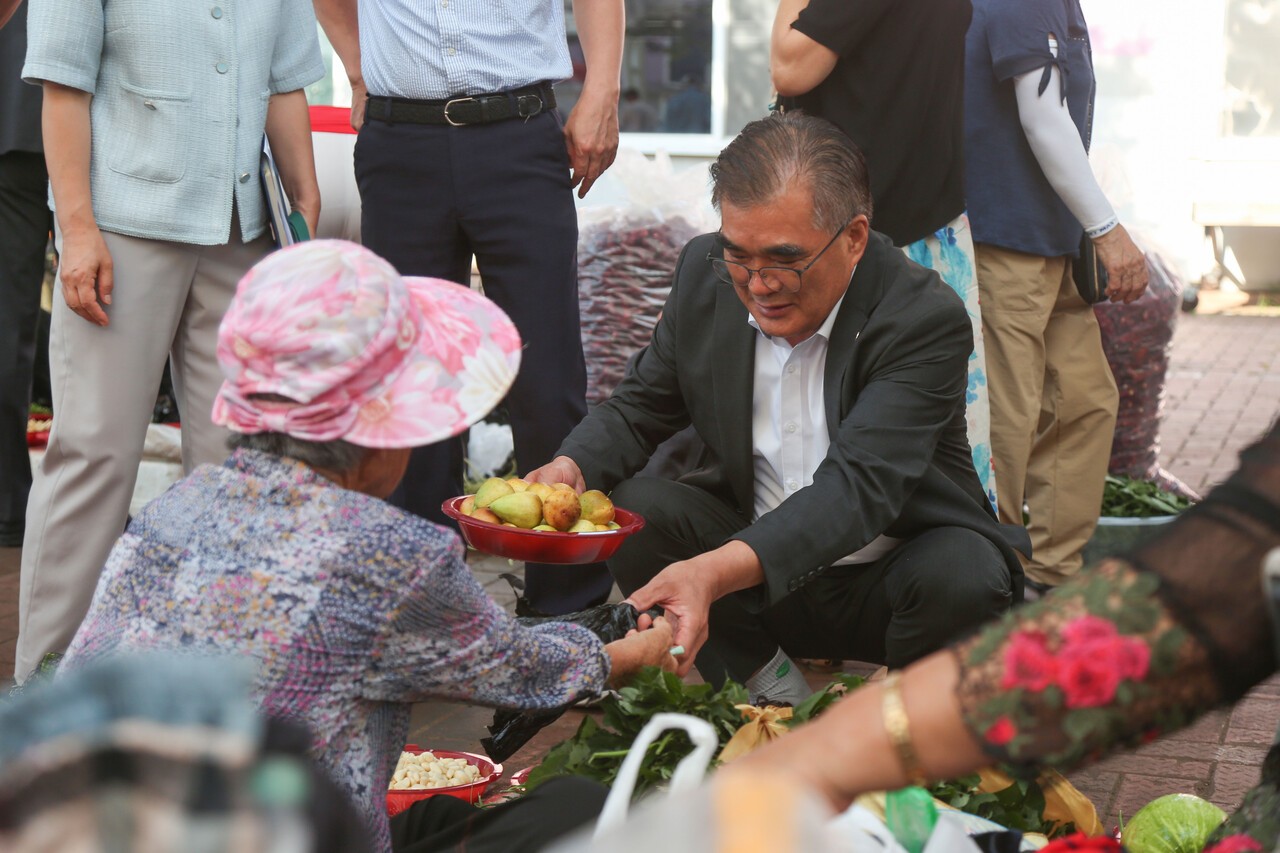 추석 명절을 맞아 지역 전통시장을 찾은 김기웅 서천군수가 한 노점 상인에게 무화과 등 과일을 구매하고 있다. [사진 서천군]